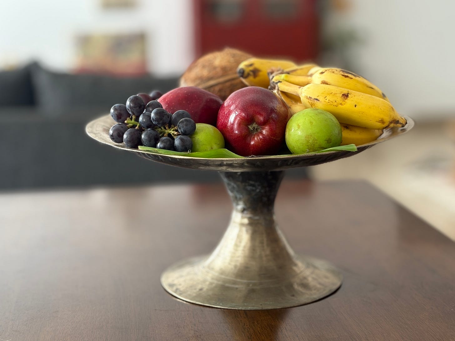 A side view of a ceremonial bell metal vessel with different fruits arranged for offering during Janmashtami, the celebration of Lord Krishna's birth.