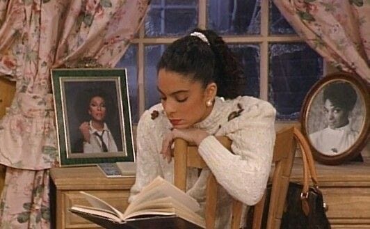 This may contain: a woman sitting in a chair reading a book