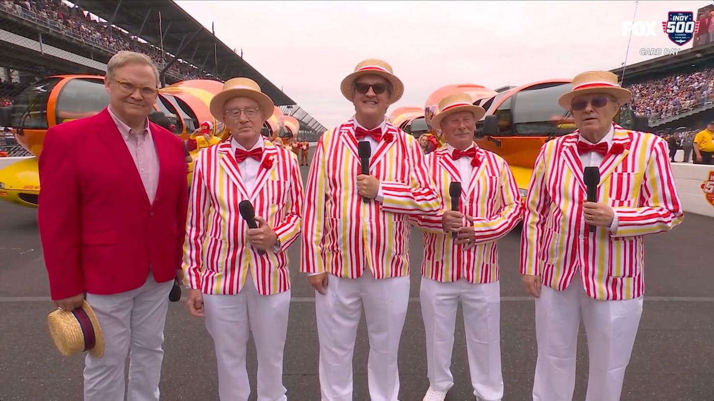 Andy Richter next to 4 guys in striped jackets and hats with microphones Andy Richter next to 4 guys in striped jackets and hats with microphones