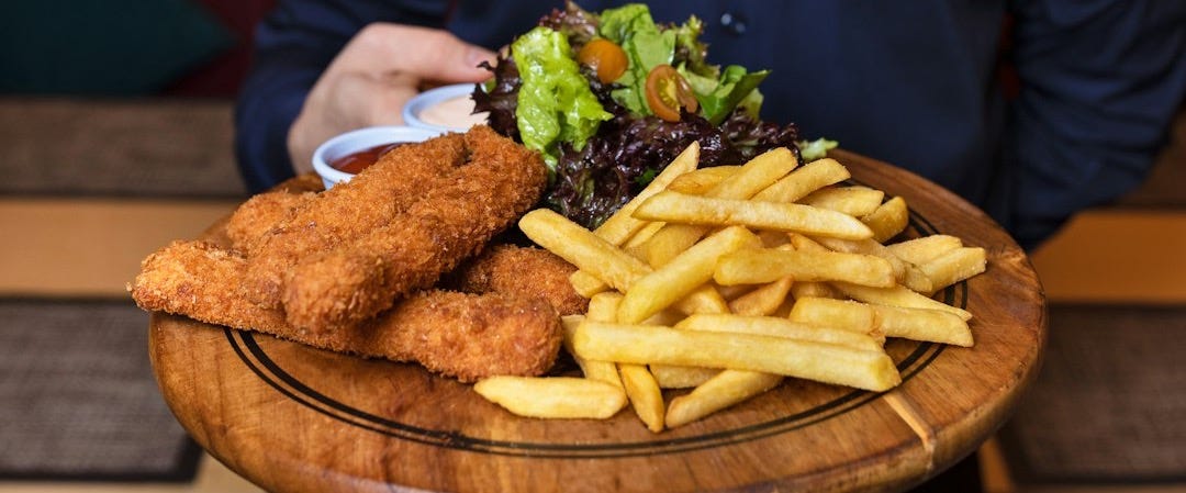 man in blue dress shirt holding brown wooden tray with fries