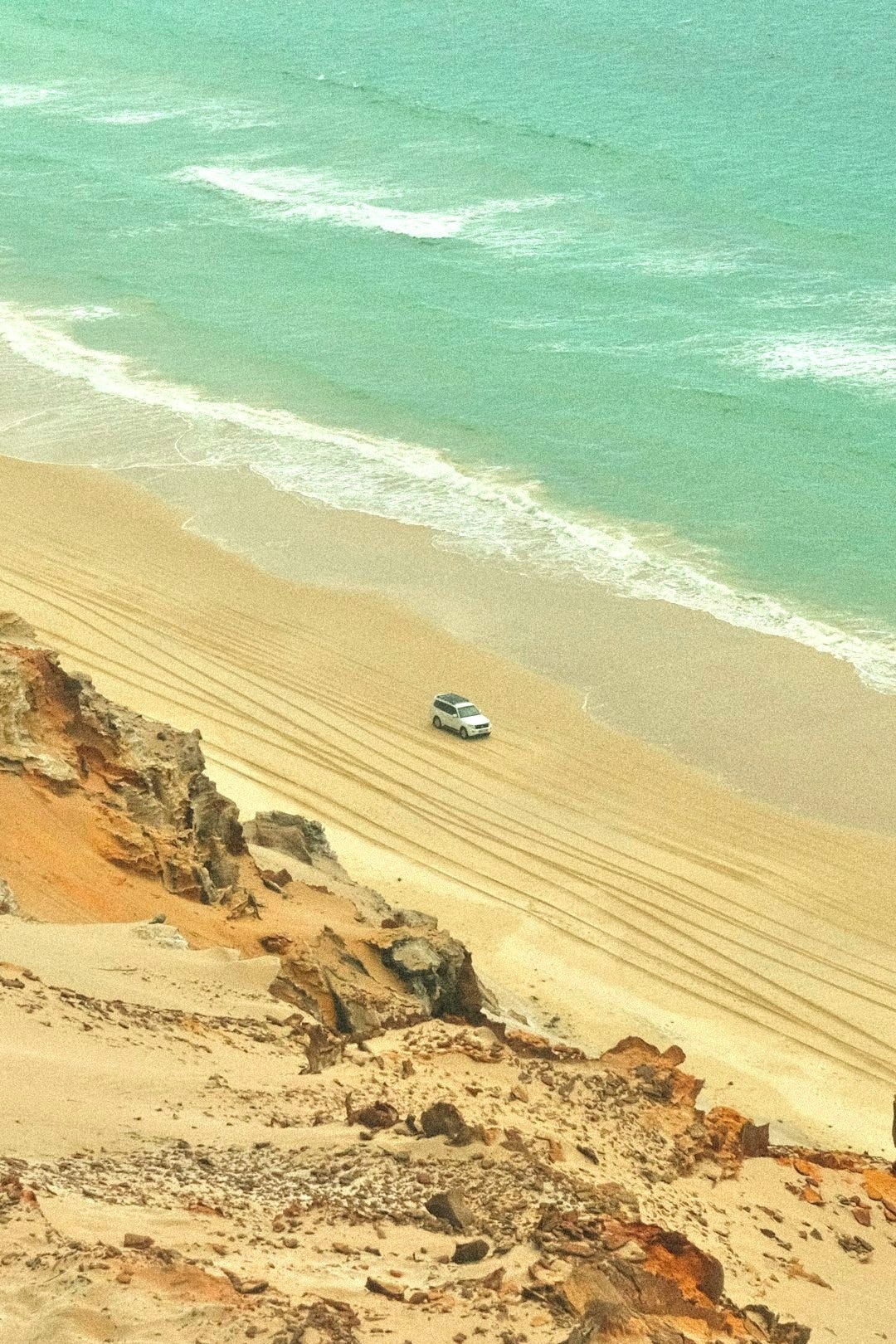 a car is parked on the beach near the water
