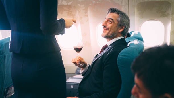 cabin crew serving food to passenger of business class in airplane - first class airplane stock pictures, royalty-free photos & images