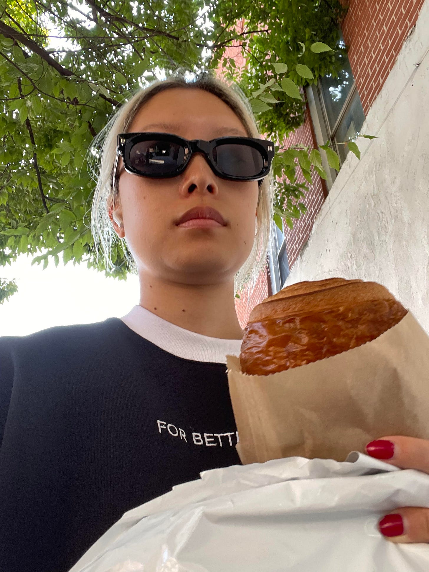 Delia Cai selfie with sunglasses walking while holding pastry Delia Cai selfie with sunglasses walking while holding pastry
