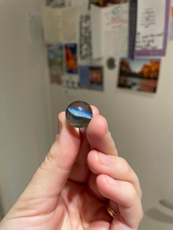 pen and notebook earrings and a blue marble