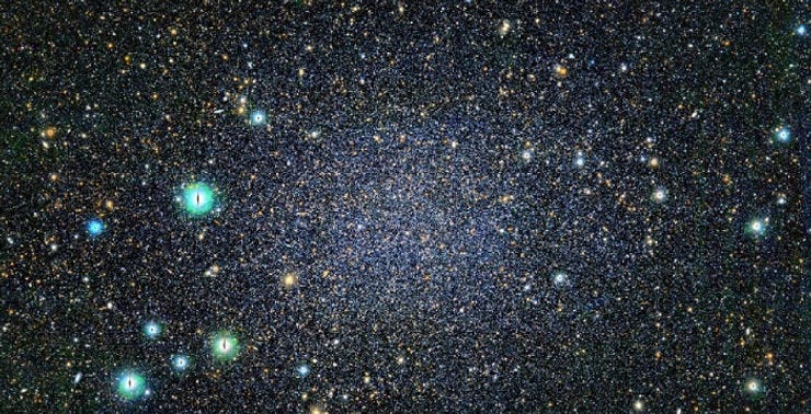 An image of the Sculptor Dwarf Galaxy taken by the Subaru Telescope. It shows a dense field of stars with a central concentration of faint, blue and white stars, indicating an older stellar population. Bright stars, varying in color from blue to yellow, are scattered across the image. The text above the image explains that the Sculptor Dwarf Galaxy is about 290,000 light-years away and has little to no recent star formation activity. An image of the Sculptor Dwarf Galaxy taken by the Subaru Telescope. It shows a dense field of stars with a central concentration of faint, blue and white stars, indicating an older stellar population. Bright stars, varying in color from blue to yellow, are scattered across the image. The text above the image explains that the Sculptor Dwarf Galaxy is about 290,000 light-years away and has little to no recent star formation activity.