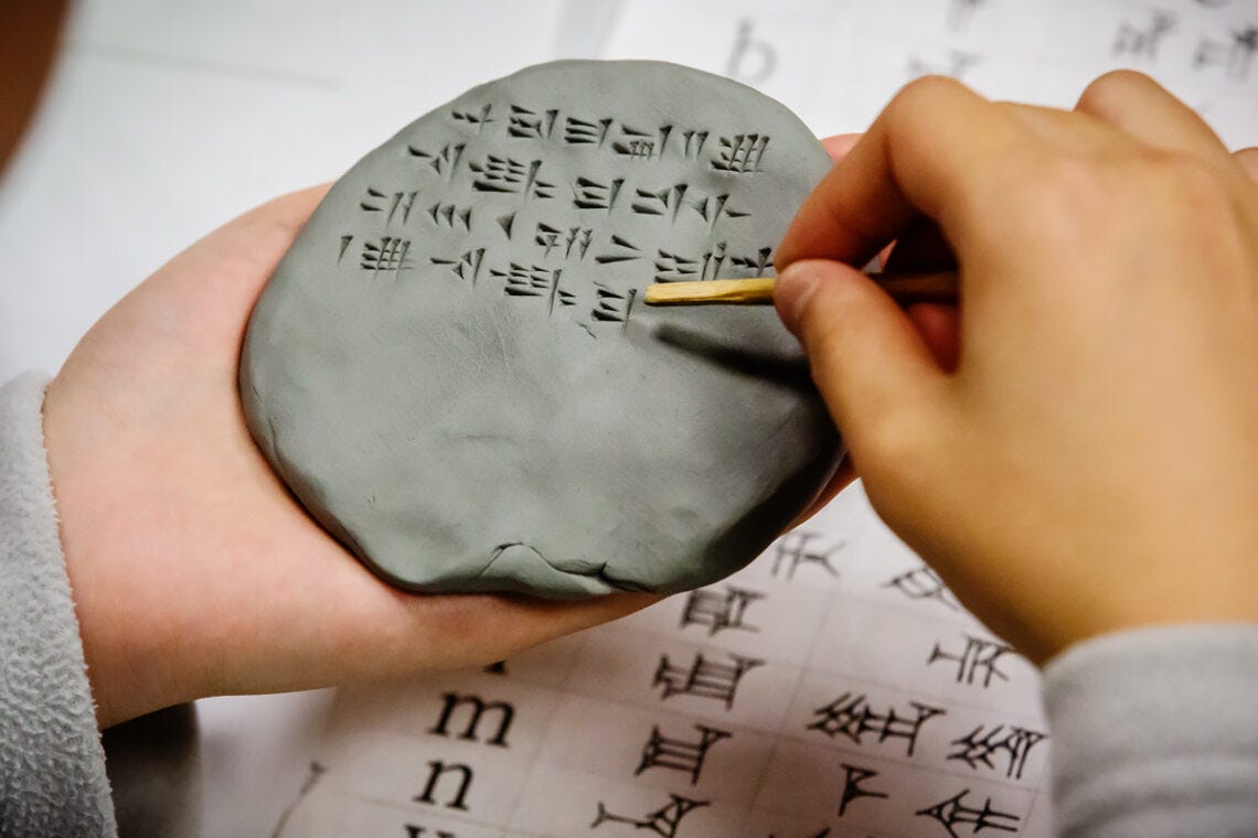 A student writes in Hittite using cuneiform symbols pressed into clay. A student writes in Hittite using cuneiform symbols pressed into clay.