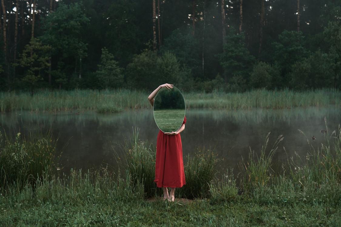 Free A Woman in Red Dress Standing on Green Grass while Holding a Mirror Stock Photo
