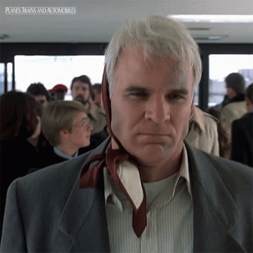a man with a tie around his neck is standing in a crowded room with planes trains and automobiles written on the bottom right
