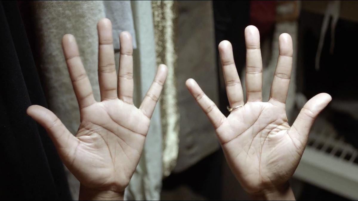 Still from "The Tuba Thieves," directed by Alison O'Daniel, showing Nyke's hands in the moment right before she signs the film's title.