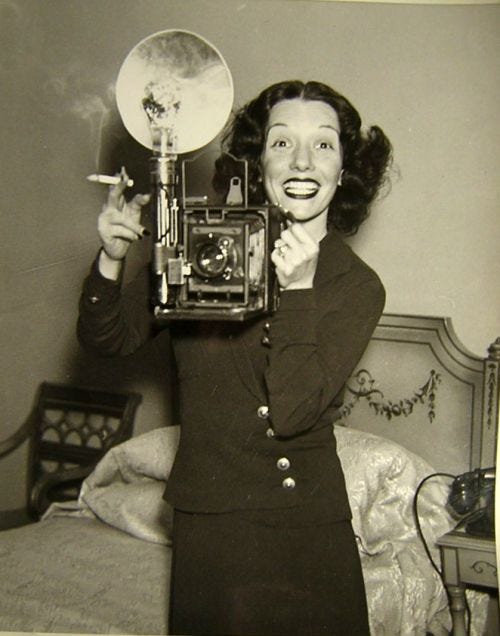 This may contain: an old black and white photo of a woman holding a camera