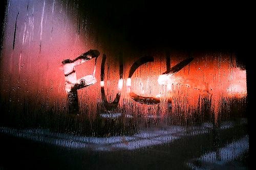 This may contain: the word hope written in wet glass on a window sill with rain drops and street lights behind it