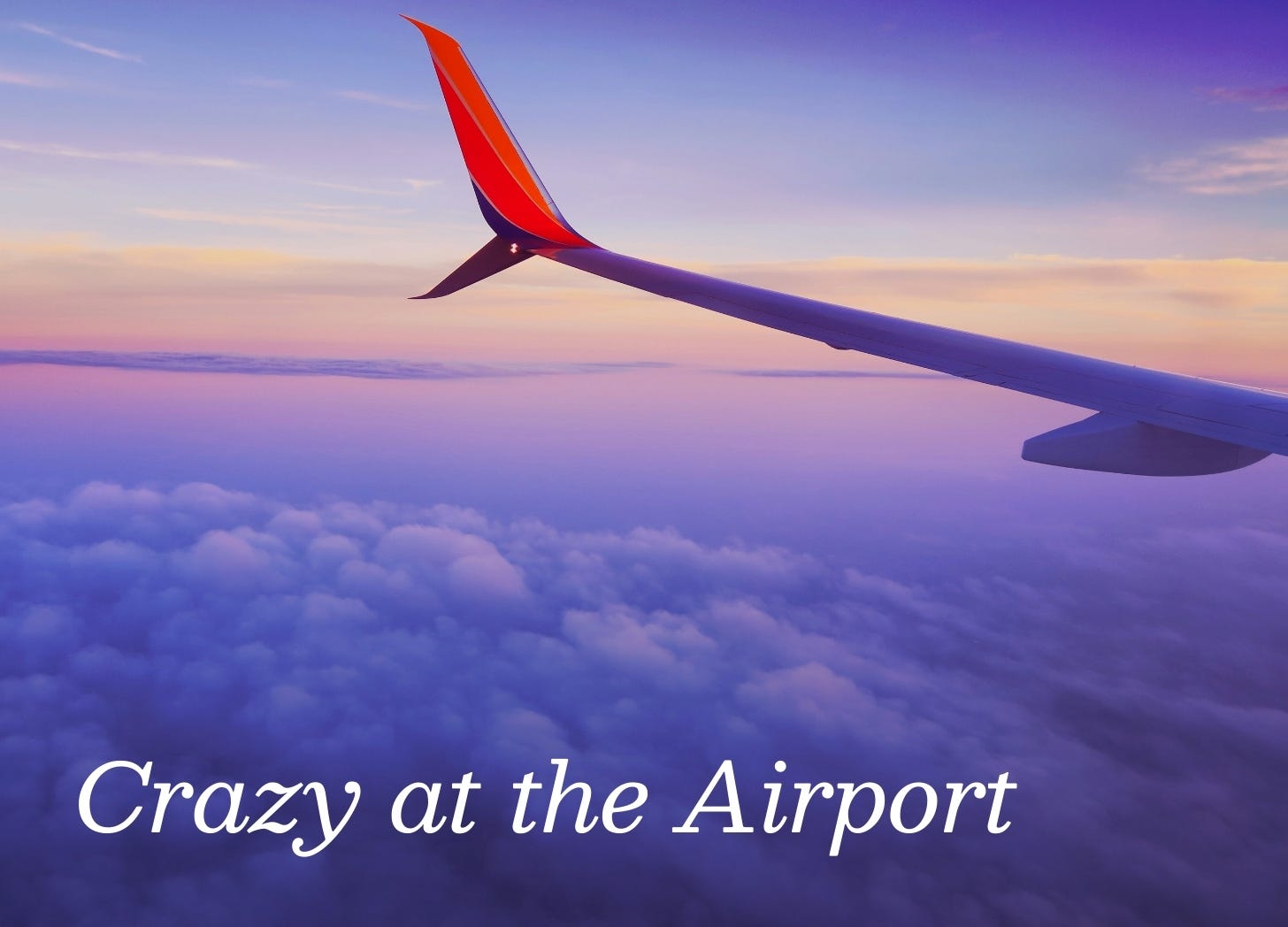 The red tip of a white airplane wing shows against a setting sun. The sky is a deep purple color. The red tip of a white airplane wing shows against a setting sun. The sky is a deep purple color.