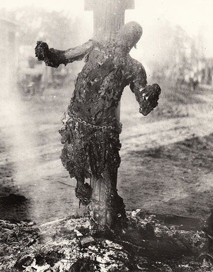 Front view of burned body of African-American man chained to pole