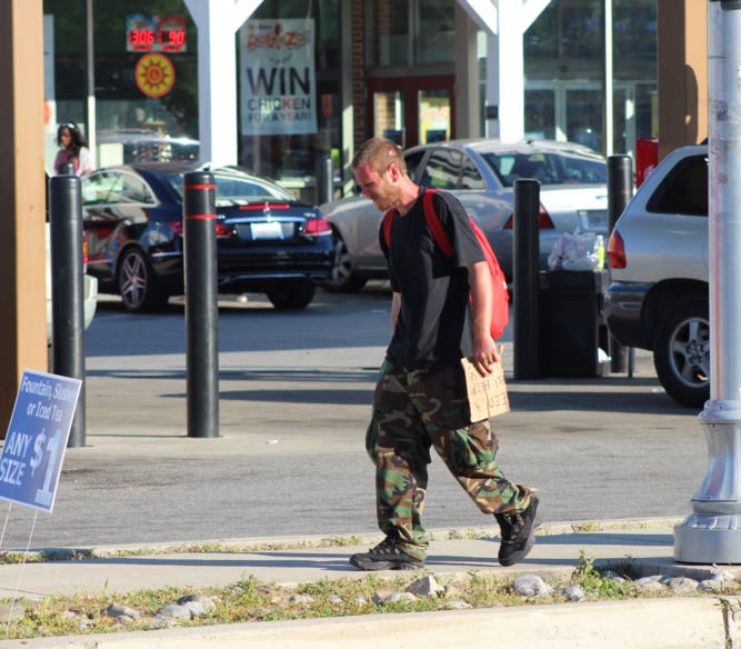 Beaten. A white panhandler with his cardboard sign in Baltimore. Beaten. A white panhandler with his cardboard sign in Baltimore.