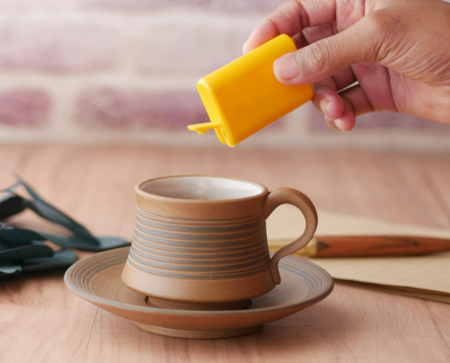 Cup of hot drink with a hand sprinkling sweetener into drink