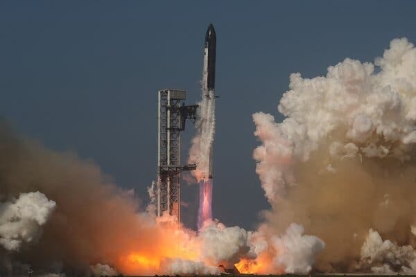 Large billows of white and gray smoke rise from orange flames at the base of a launchpad as a rocket lifts off.