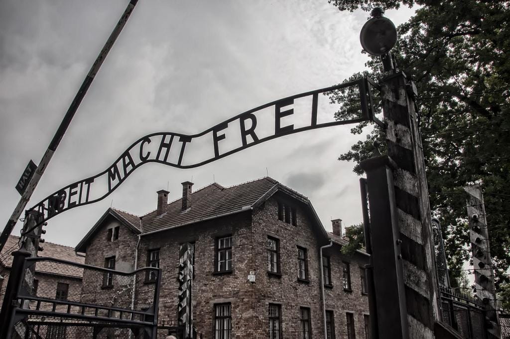 A black and white photo of the Auschwitz sign above the camp entrance that says, Arbeit Macht Frei." A black and white photo of the Auschwitz sign above the camp entrance that says, Arbeit Macht Frei."