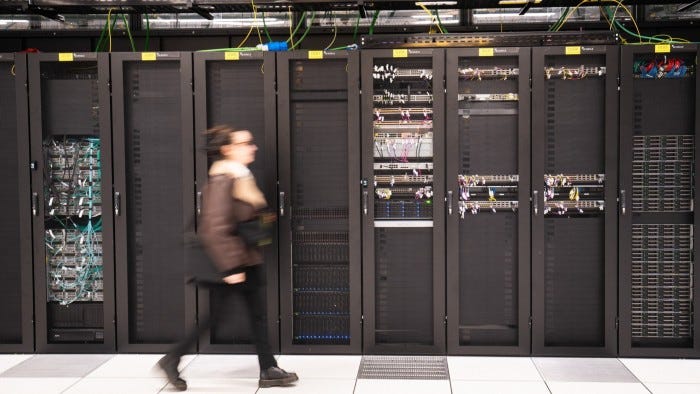 A person walks past a computer bay at a data centre
