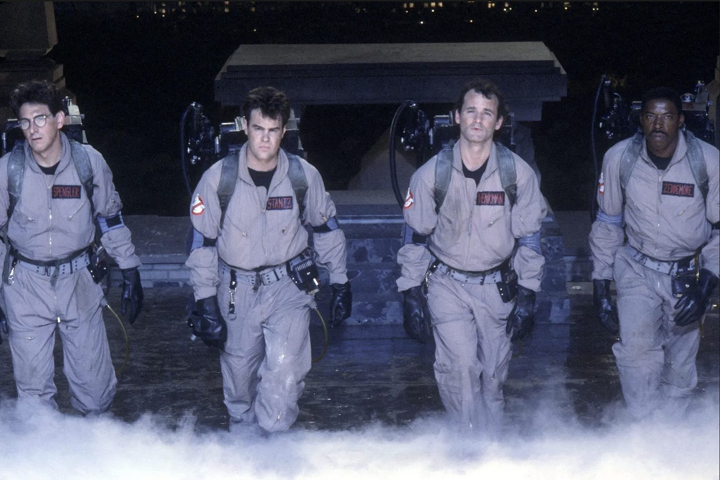 The four ghostbusters from the movie "Ghostbusters" marching forward on a mission to help