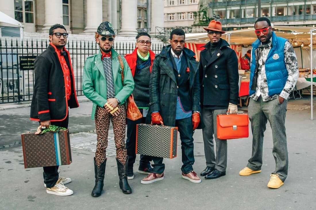 Virgil Abloh (far right) with his then-employer Kanye West (center, holding briefcase) at Paris Fashion Week in 2009.