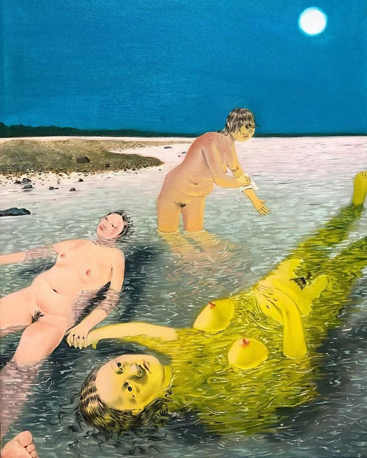 This may contain: two people are in the water with one person laying on the ground and another standing