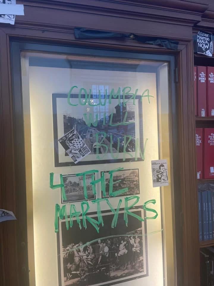 Graffiti over framed photos in Columbia library.
