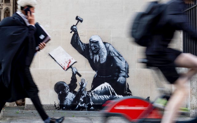 An undated photo released by Banksy of the new artwork by the artist which portrays a judge beating a protester with a gavel at the Royal Courts of Justice in London. (Banksy via AP)