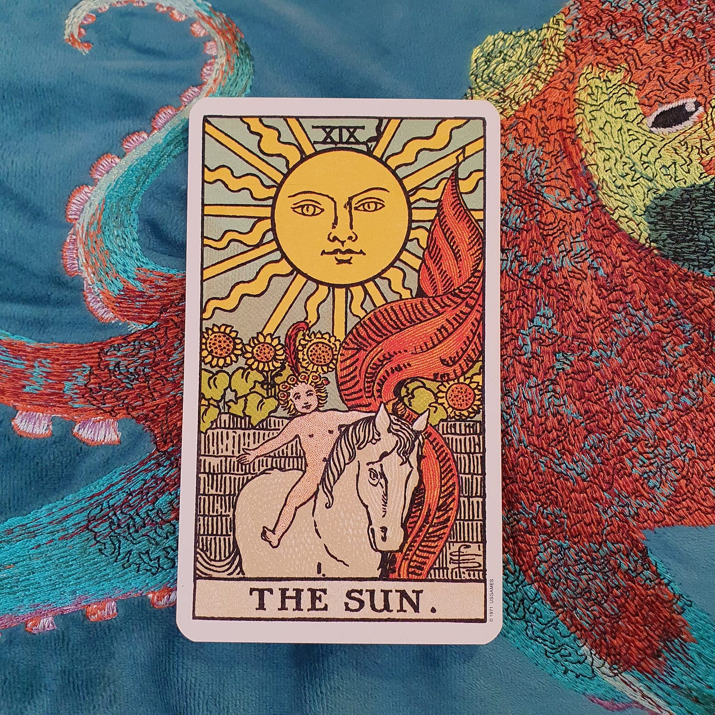 The Sun tarot card from a Rider-Waite-Smith style deck on embroidered blue fabric for Callie Kazumi’s Tarot DMs interview.