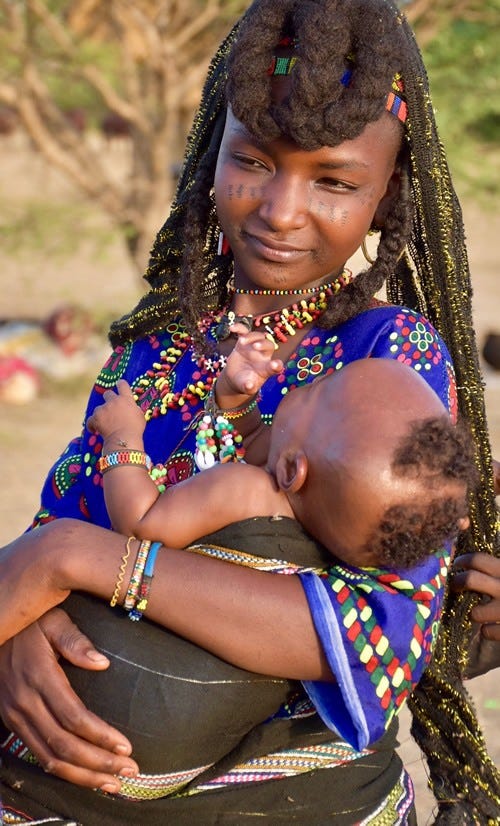 Lovette Jallow wearing yellow during a cultural gathering—scarification visible as a marker of Fulani ancestral lineage and belonging.