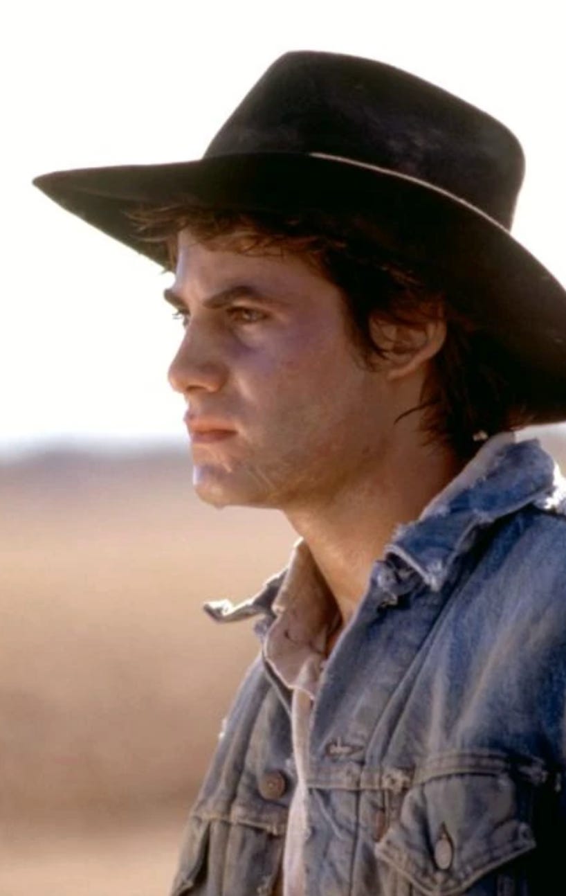 near dark still; good looking guy in cowboy hat stares soulfully into distance