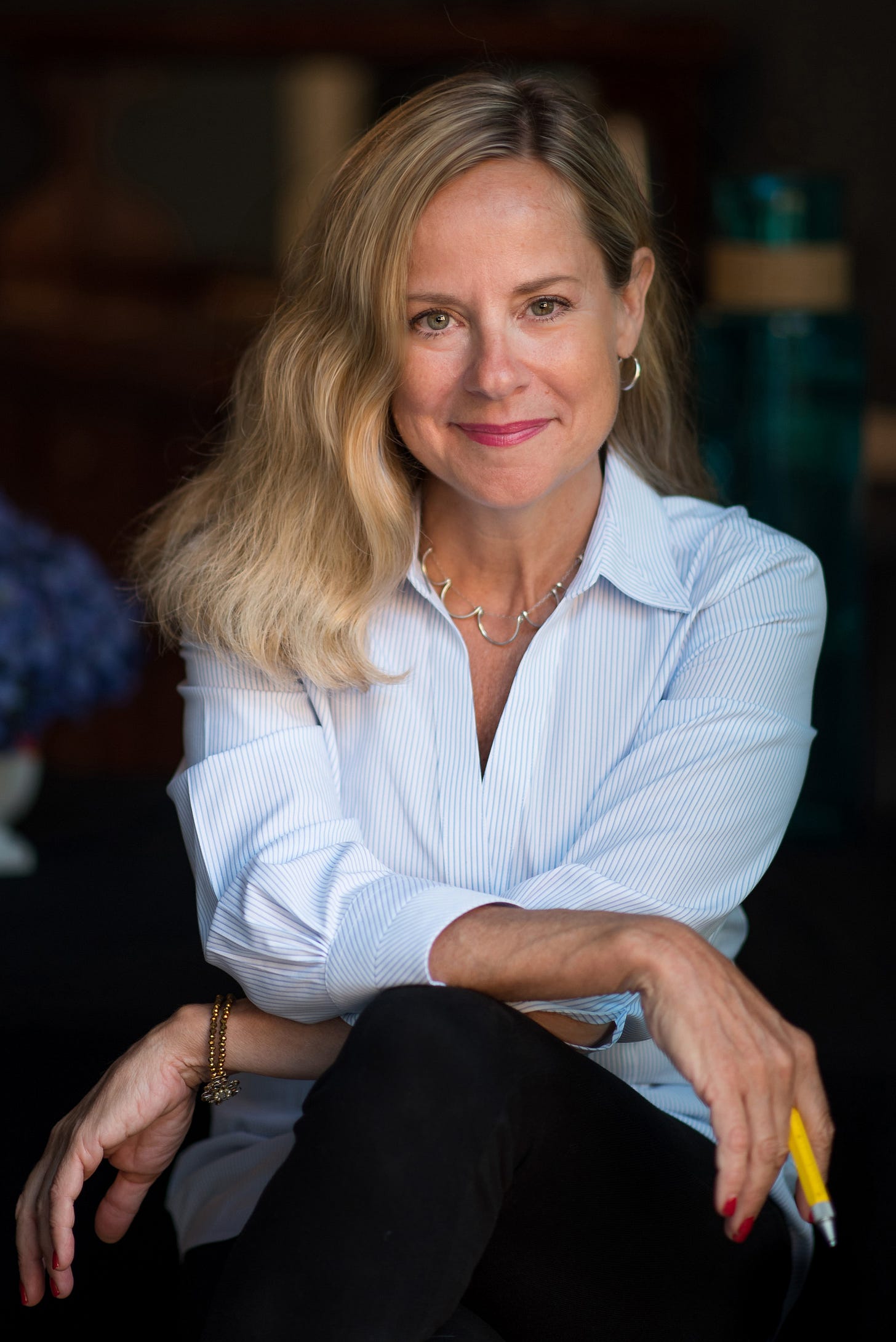 Blonde woman in blue and white striped button down shirt smiling