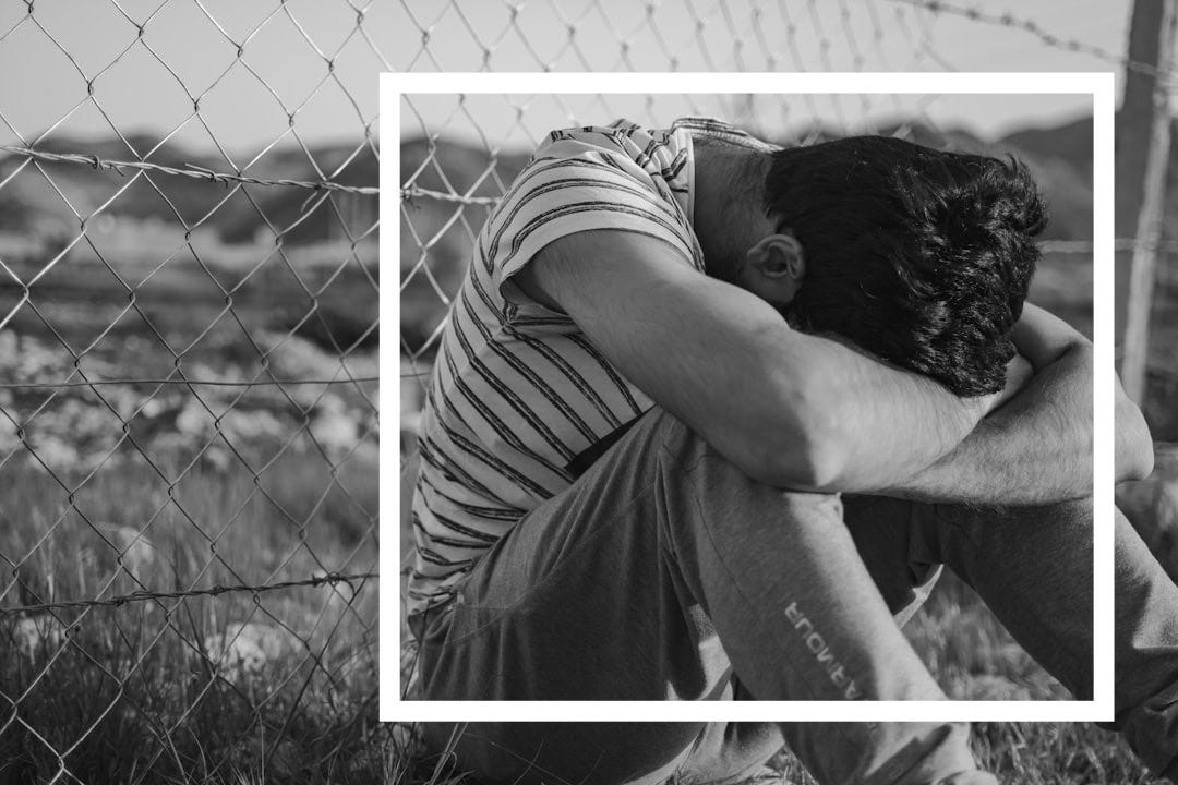 man in black and white stripe t-shirt leaning on chain link fence