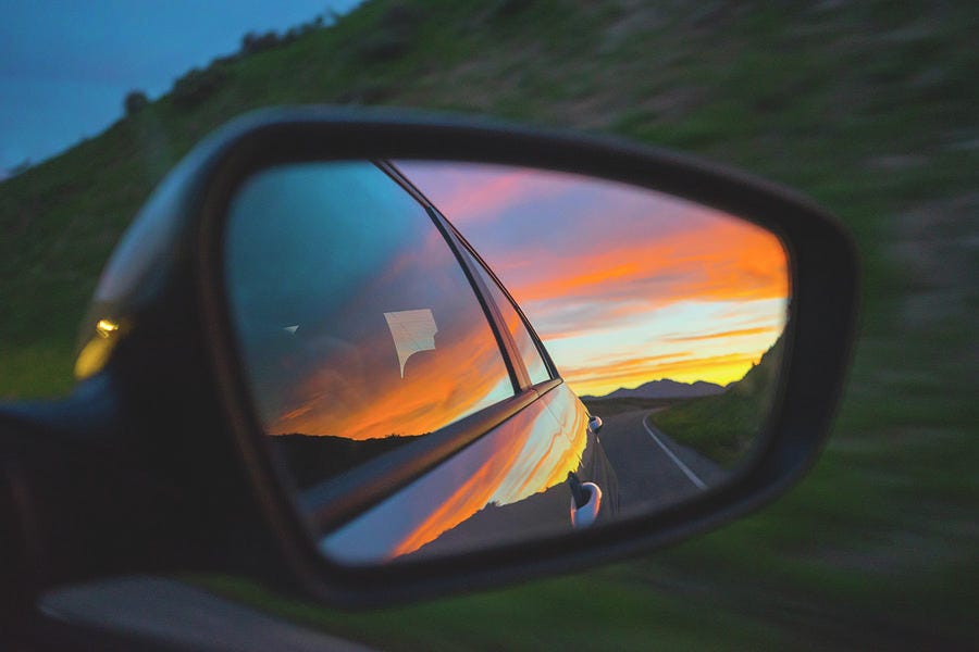 Colorful Sunset Sky In A Rear-view Mirror At Night by Cavan Images