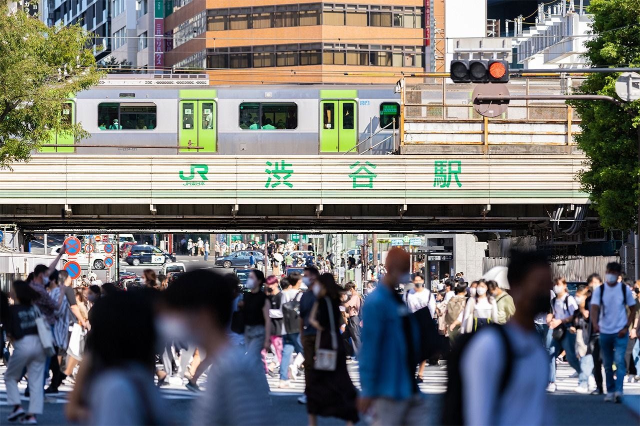 A Yamanote line passes near the scramble crossing outside Shibuya Station. (© Pixta)