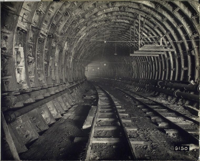 Black and white photograph of the interior of a large train tunnel under construction