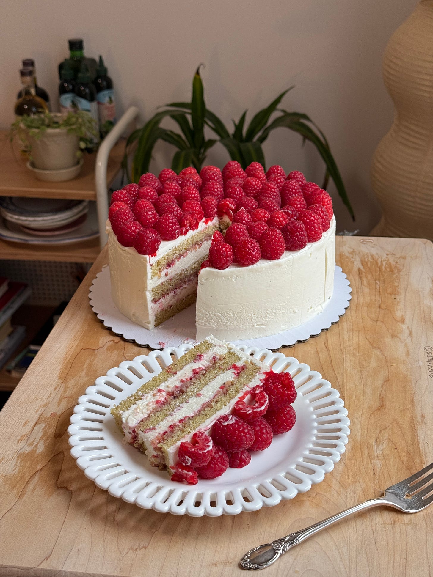 a raspberry pistachio cake with a slice next to it on a plate