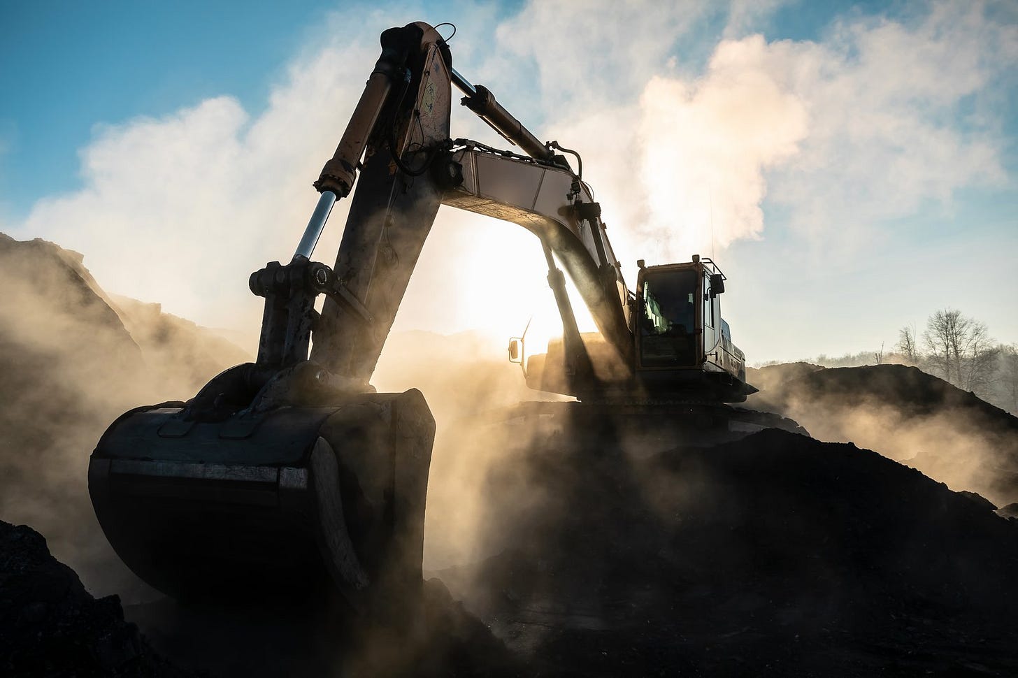 An excavator digging at a dusty site