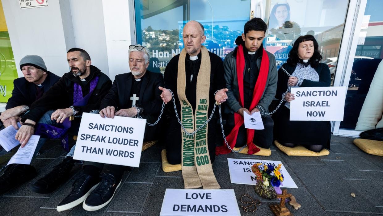 Clergy from the Wellington Anglican Dioceses and a member of the Wellington Catholic Church chain themselves to Nicola Willis’ office in Johnsonville.