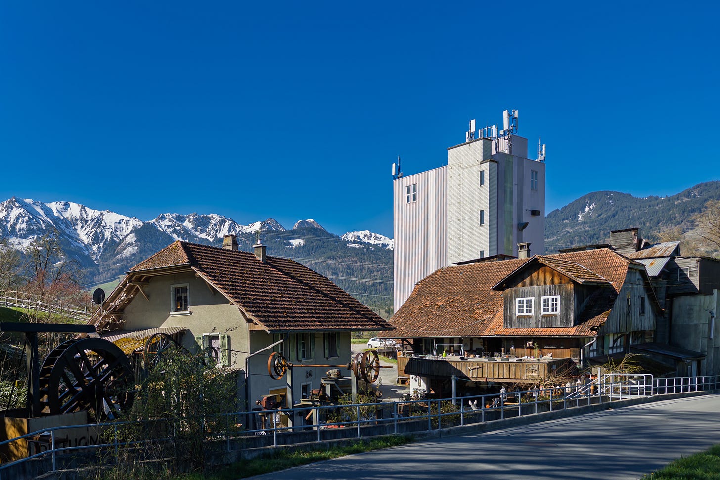 Gesamtansicht der Dittligmühle vor den verschneiten Berggipfeln der Gantrisch-Kette. Im Vordergrund stehen das alte Mühlegebäude mit Verkaufsladen und Kaffeestübchen sowie ganz links das laufende historische Mühlrad; dahinter ragt der moderne, helle Mühleturm auf. Gesamtansicht der Dittligmühle vor den verschneiten Berggipfeln der Gantrisch-Kette. Im Vordergrund stehen das alte Mühlegebäude mit Verkaufsladen und Kaffeestübchen sowie ganz links das laufende historische Mühlrad; dahinter ragt der moderne, helle Mühleturm auf.
