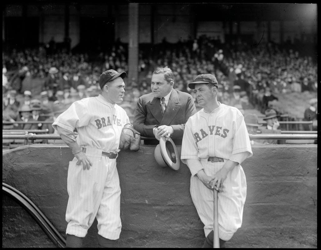 Rogers Hornsby and a Braves coach lean on the barrier wall for a discussion with Emil Fuchs.