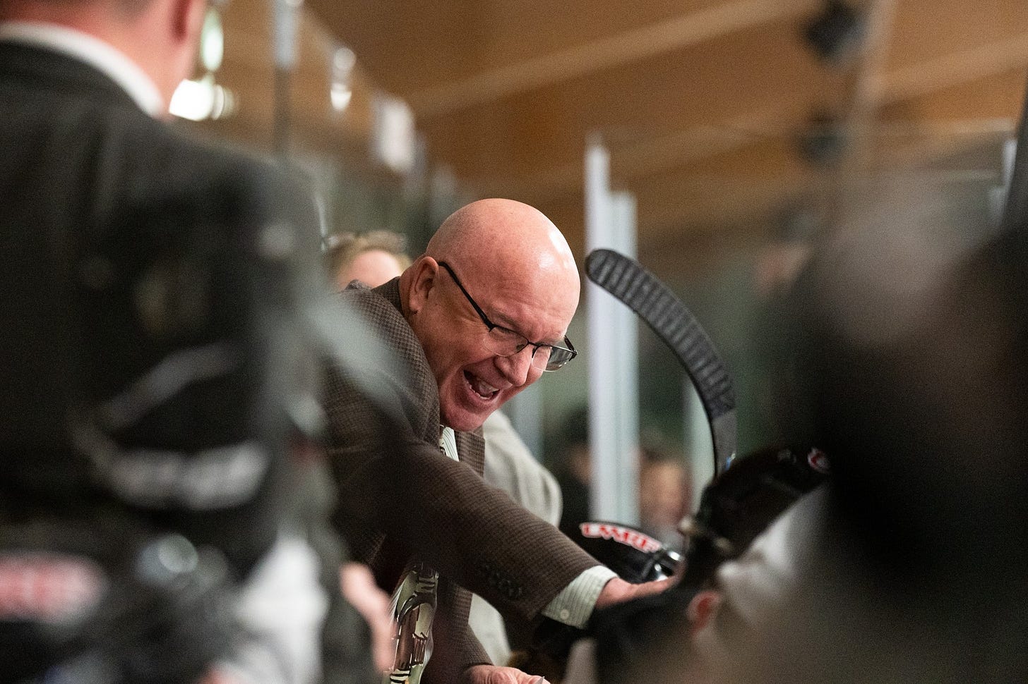 Joe Cranston in a suit taps the head of one of his players Joe Cranston in a suit taps the head of one of his players