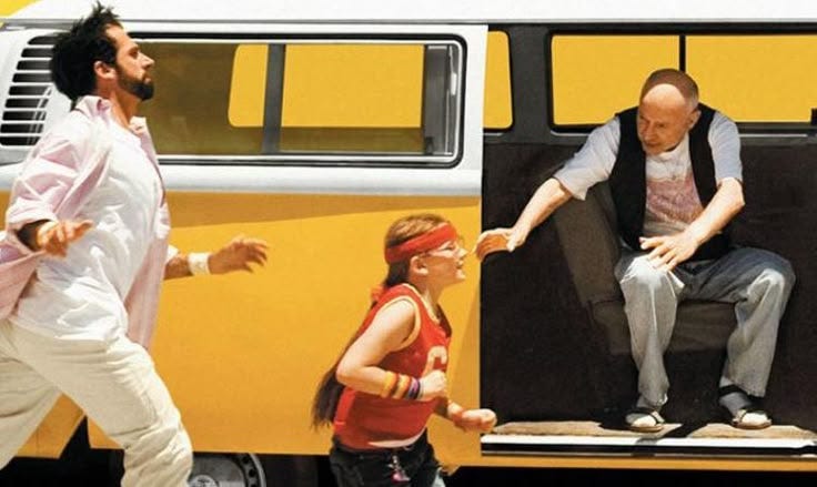 This may contain: two men and a woman are running in front of a bus with the door open