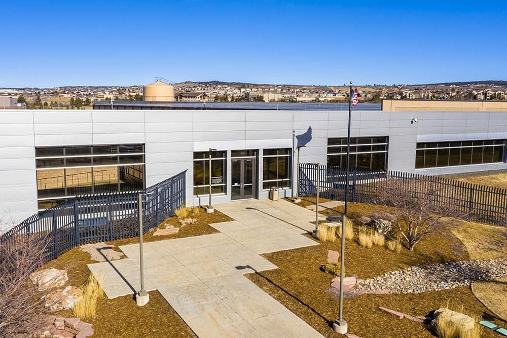 A modern data center building with a grey facade and landscaped entrance