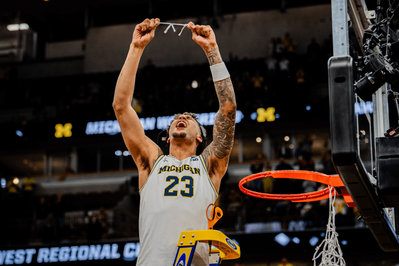 Yaxel Lendeborg raises a piece of the net above his head.