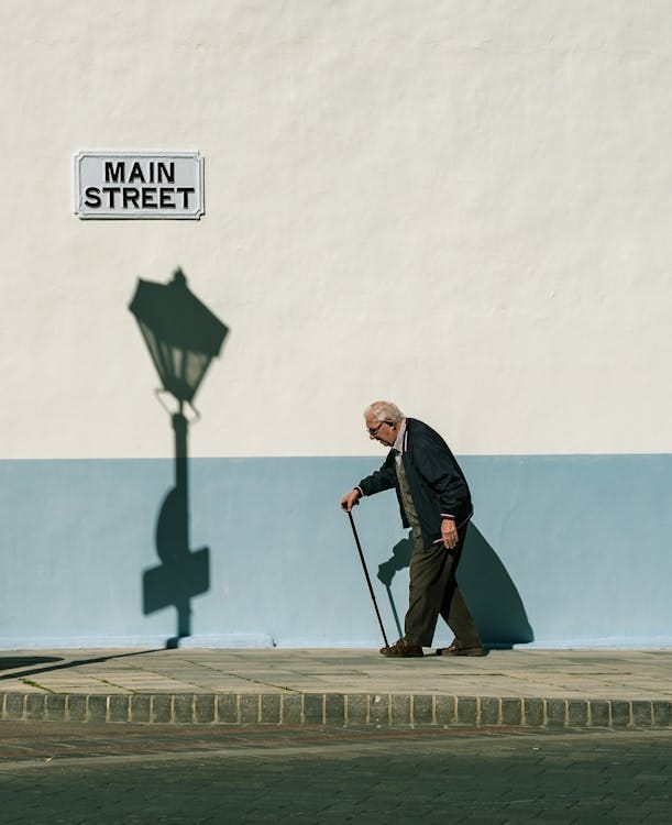 Free An Elderly Man Walking on the Sidewalk Stock Photo