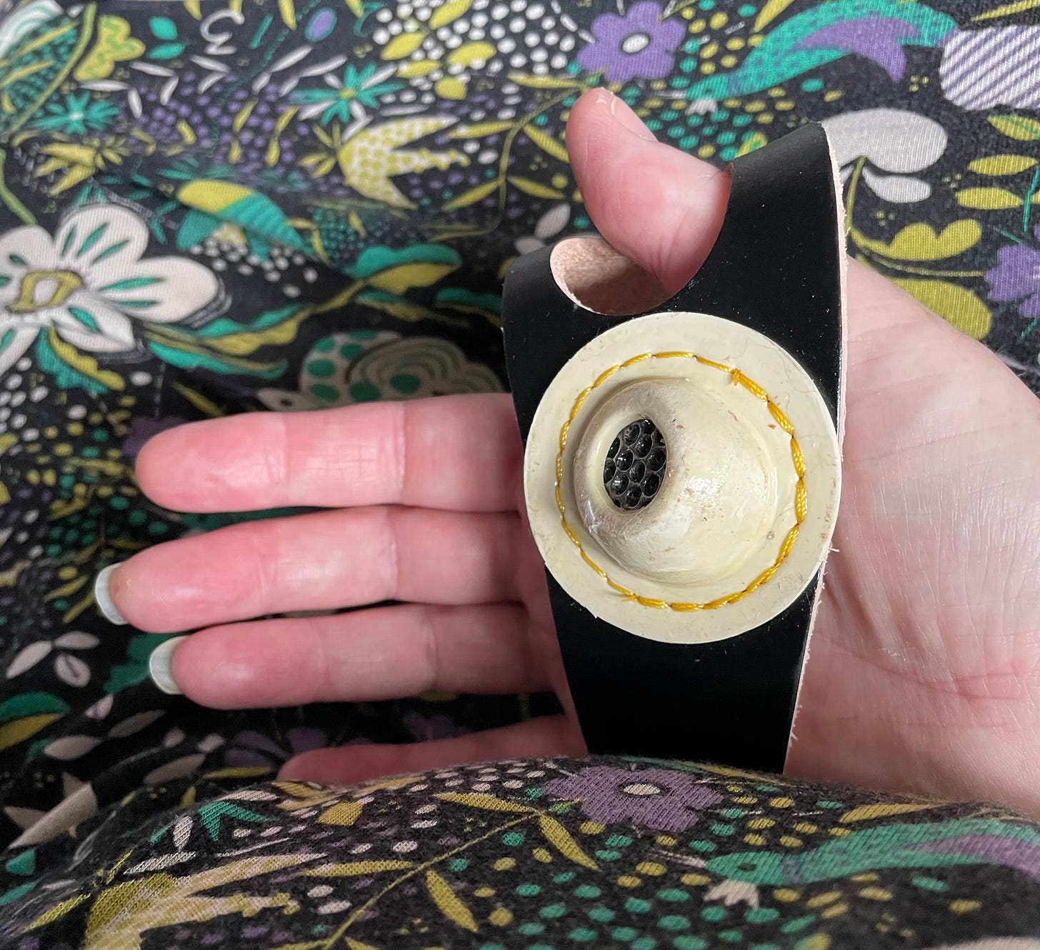 A leather band with a hard metalled section fastened around a hand that is too small for it