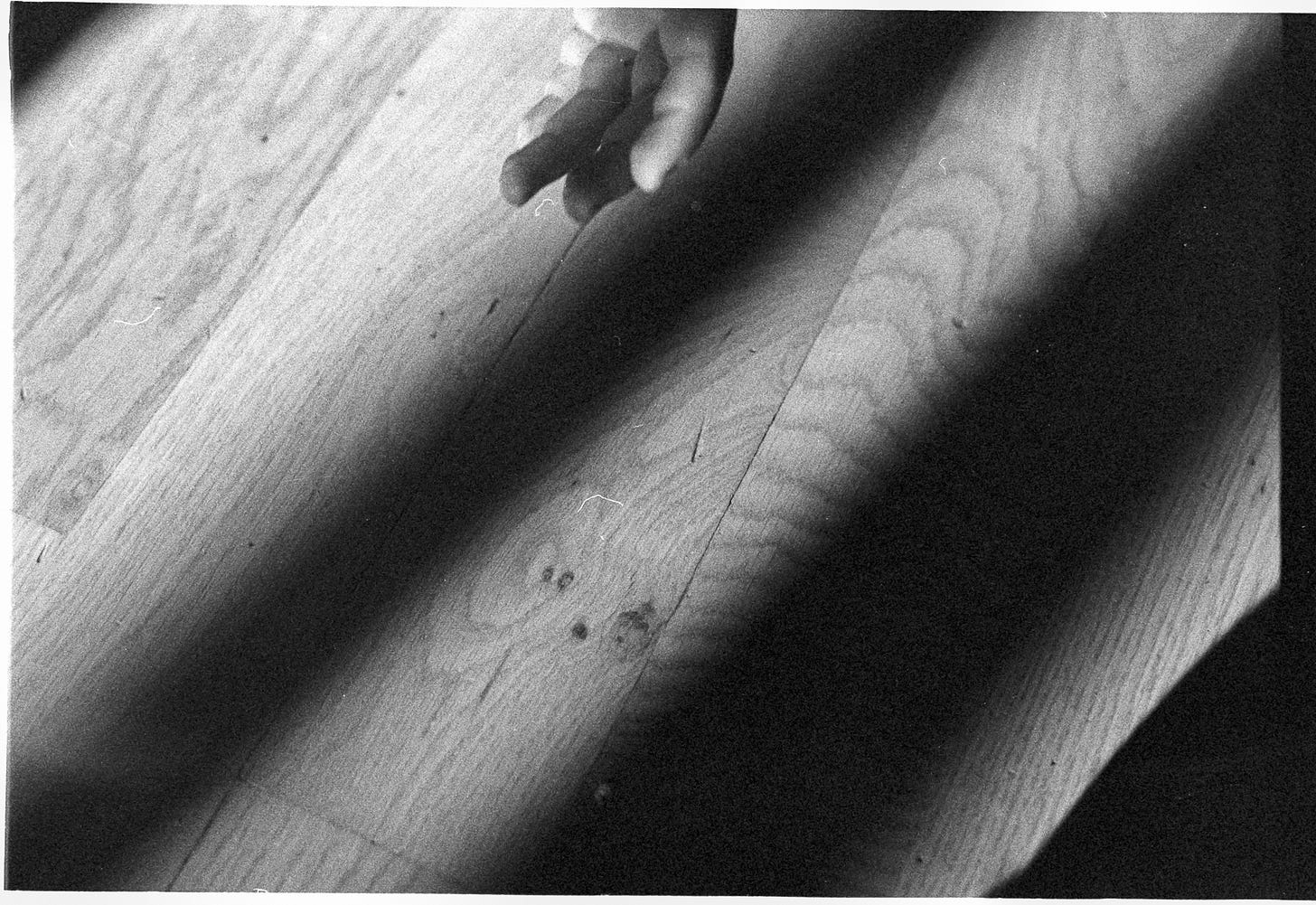 A girl's fingers reach in from top of frame on a background of floorboards in pretty evening light. A girl's fingers reach in from top of frame on a background of floorboards in pretty evening light.