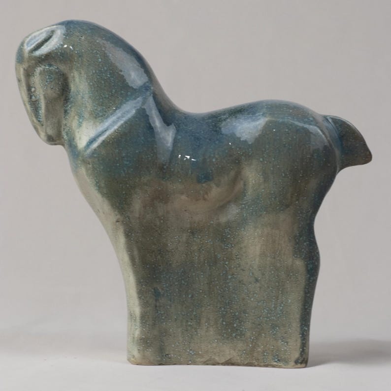 May include: A ceramic horse sculpture in shades of blue and gray. The horse is depicted in a stylized pose, with its head turned and its body arched. The sculpture has a glossy finish and a textured surface, adding depth and visual interest. May include: A ceramic horse sculpture in shades of blue and gray. The horse is depicted in a stylized pose, with its head turned and its body arched. The sculpture has a glossy finish and a textured surface, adding depth and visual interest.