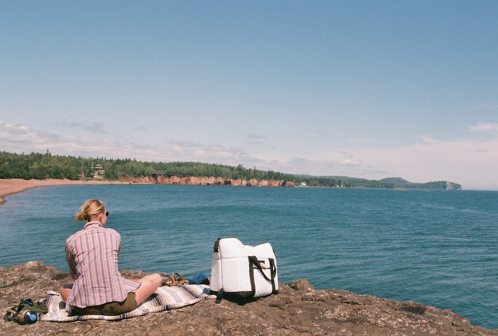 Picture shows Lisa's friend sitting on a cliff overlooking the lake with a pink beach in the background. Picture shows Lisa's friend sitting on a cliff overlooking the lake with a pink beach in the background.