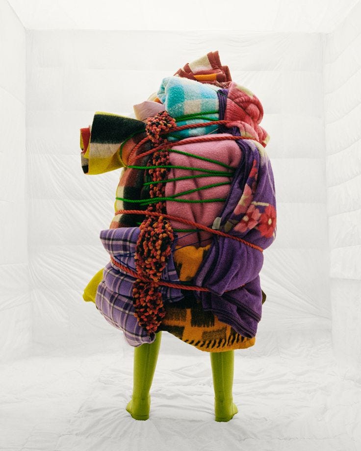 This may contain: a large pile of cloths sitting on top of a green stool in front of a white backdrop This may contain: a large pile of cloths sitting on top of a green stool in front of a white backdrop